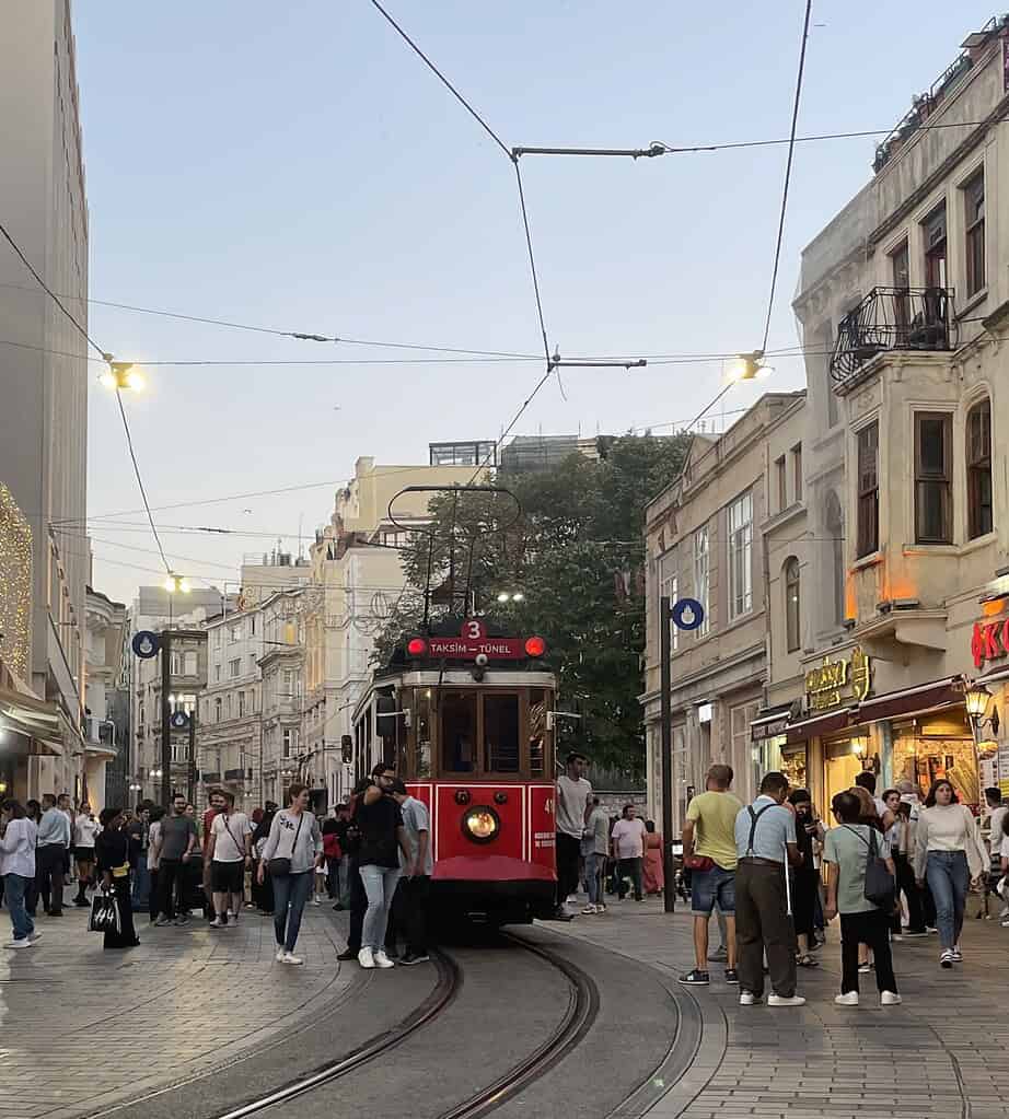 Tram passing through Beyoglu in Istanbul during the evening, surrounded by locals and tourists walking along the street.