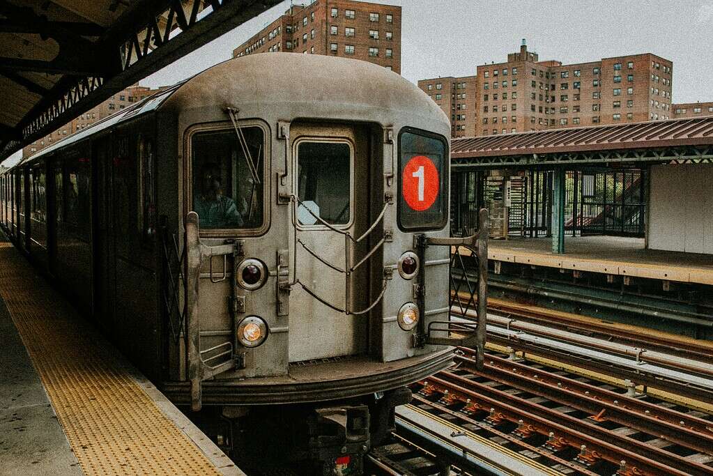 Subway train arriving at a New York City station with commuters waiting on the platform